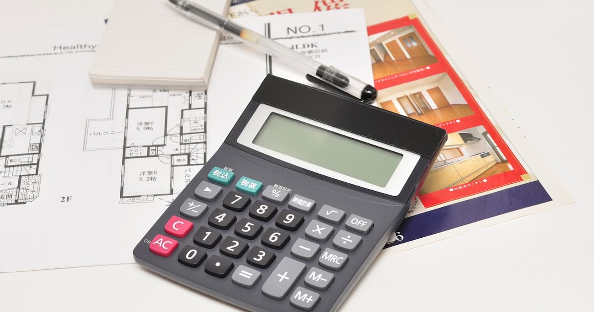電卓とメモ帳と住宅の写真